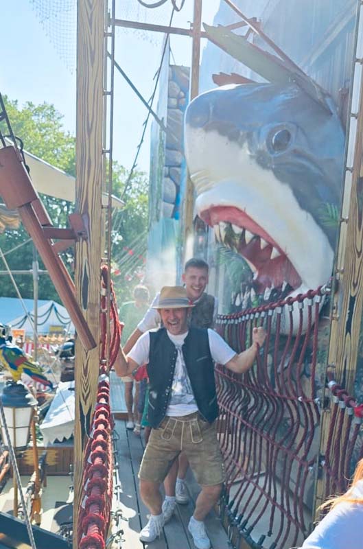 Mann mit Hut läuft lachend durch ein Fahrgeschäft mit Haifischmotiv