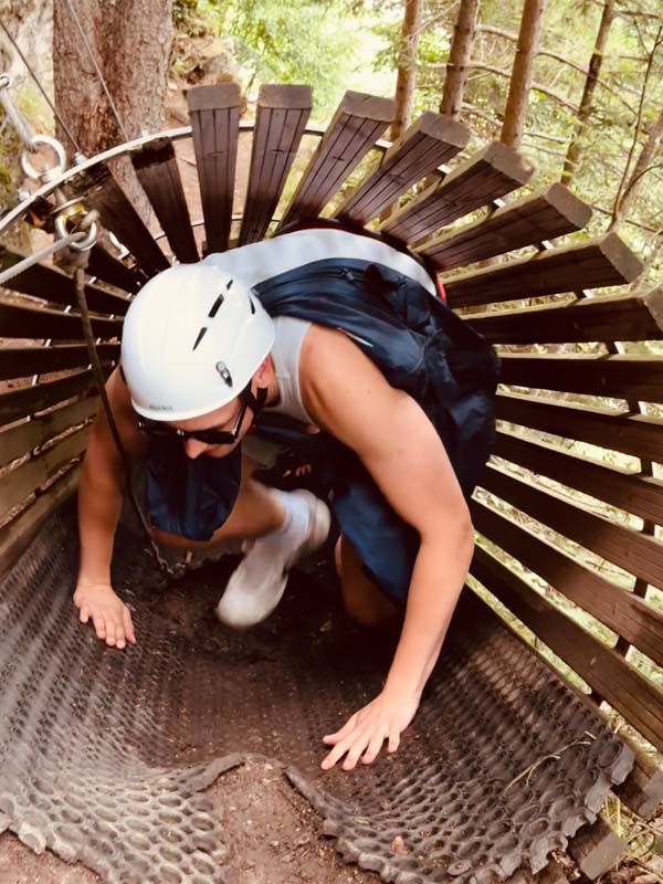 Person kriecht durch ein enges Kletterhindernis mit Helm