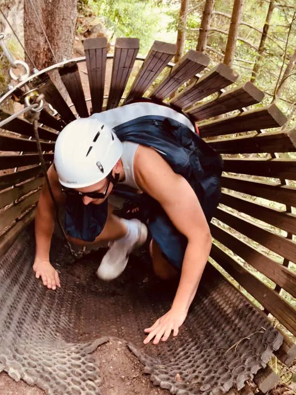 Person kriecht durch ein enges Kletterhindernis mit Helm