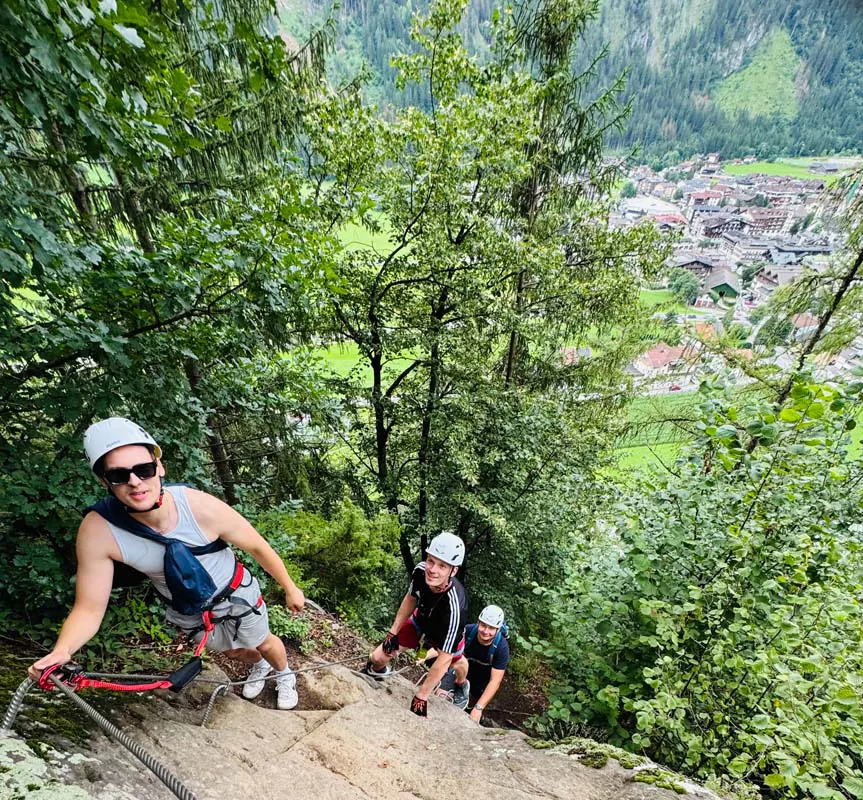 Zwei Männer klettern mit Helm und Sicherung an einer Felswand