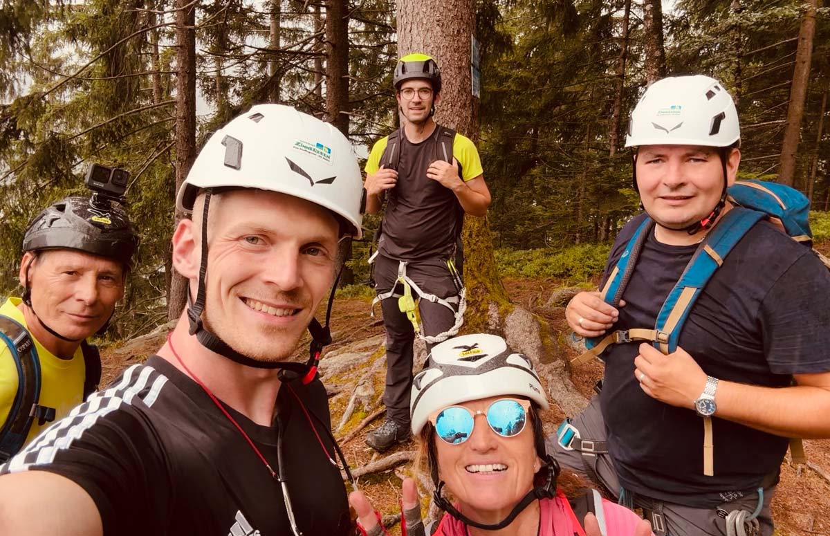 Drei Personen mit Helmen machen Selfie bei einer Klettertour