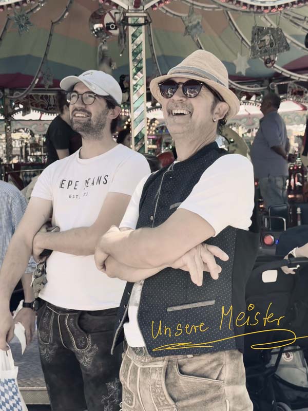 Zwei Männer lachen bei sonnigem Wetter auf einem Festgelände