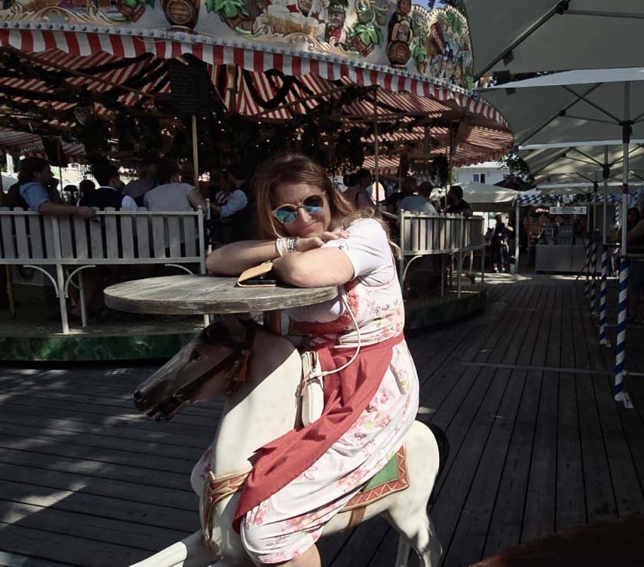 Frau in Tracht sitzt entspannt an einem Tisch auf einem Volksfest