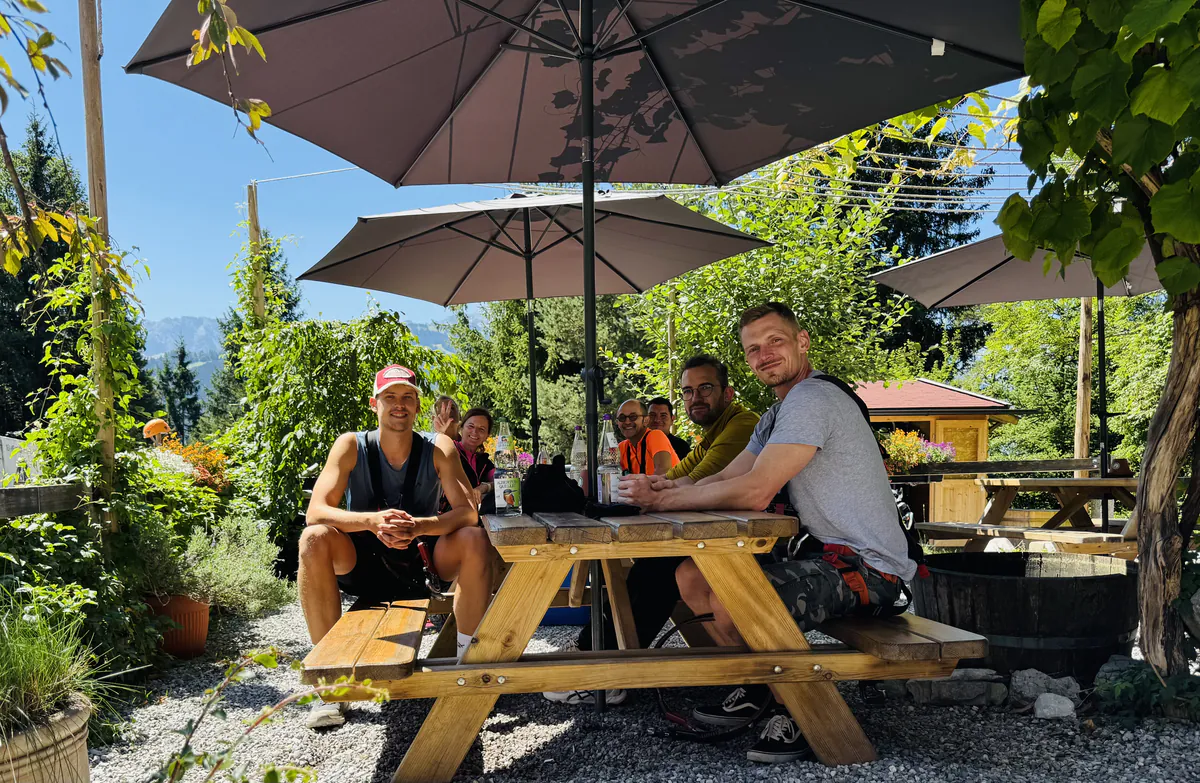 Das Team macht Pause an einem Biertisch unter Sonnenschirmen
