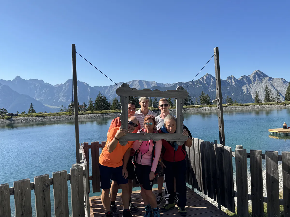 Das Team schaut durch einen Holzbilderrahmen an einem Bergsee