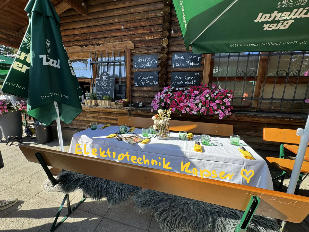 Festlich gedeckte Tafel mit Banner von Elektrotechnik Kapser auf der Almterrasse