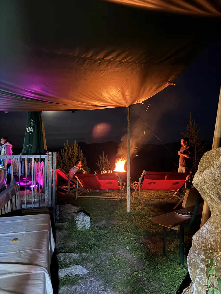Lagerfeuer und Liegestühle unter einem Sonnensegel am Abend