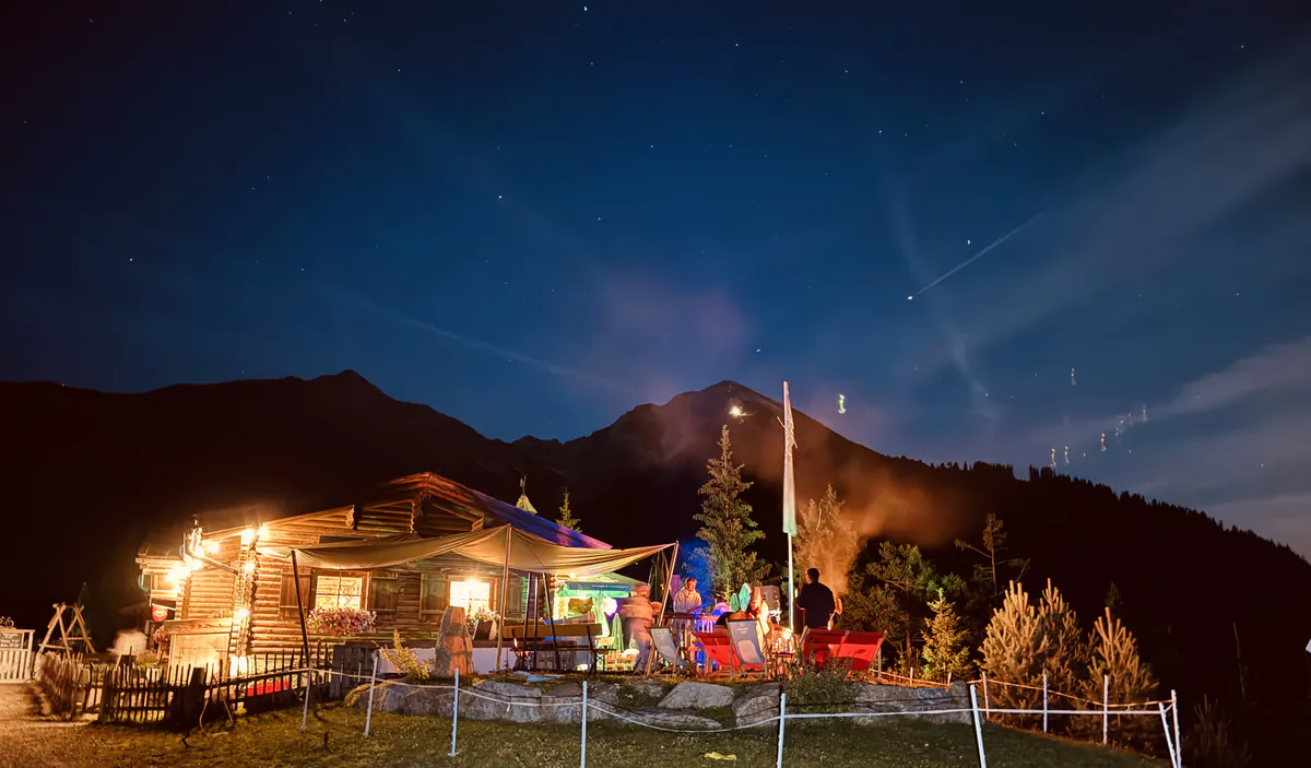 Nachtaufnahme der beleuchteten Hütte unter dem Sternenhimmel