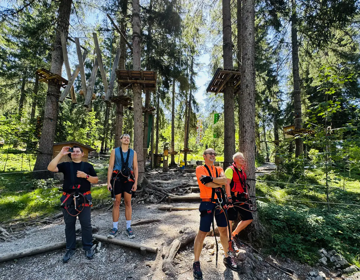 Vier Kollegen in Klettergurten stehen vor dem Einstieg in den Kletterwald