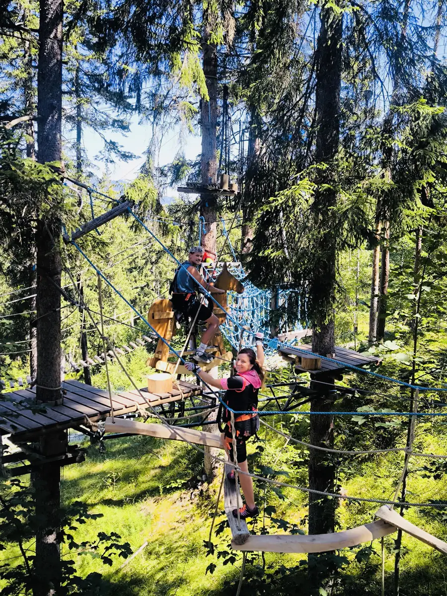 Zwei Kollegen sichern sich auf einer Plattform im Kletterwald